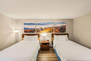 a hotel room with two beds and two lamps at Days Inn by Wyndham Raleigh-Airport-Research Triangle Park in Morrisville +14 photos
