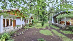 a yard in front of a house with trees at Tangkoko Hideaway Cottage in Pulau Mogogimbun