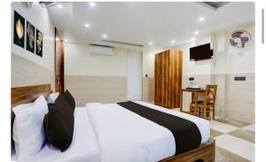 a bedroom with a large white bed and a desk at Hotel Elite Inn in Dehradun