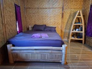 a bedroom with a bed with purple sheets at Bale Gantar in Sembalun Lawang