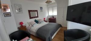 a bedroom with a bed and two chairs and a television at Les villégiatures de Muse in Saint-Marcouf