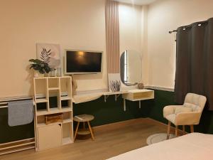 a room with a bed and a television and a chair at Enjoyo Getaway in Bangkok