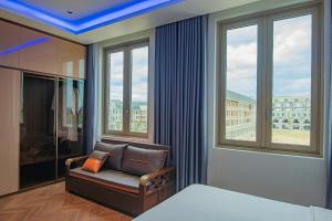 a bedroom with a bed and a chair and windows at Villa 5 brs Bao Ninh Legend walk street in Dong Hoi +13 photos