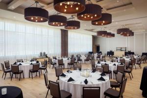 a banquet hall with white tables and chairs and chandeliers at Canopy By Hilton Sioux Falls Downtown in Sioux Falls