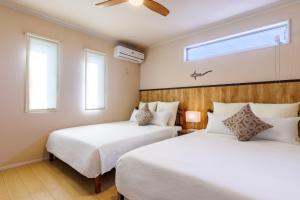 two beds in a room with two windows at YANBARU Villa 葵扇-KISEN- in Motobu