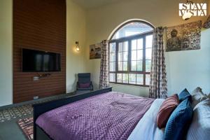 a bedroom with a bed and a tv and a window at StayVista at Golden Ridge - Pool, BBQ, Bonfire in Jaisingpur