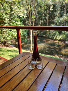 a bottle and two glasses sitting on a wooden table at Chilverton Cottages in Ravenshoe +16 photos