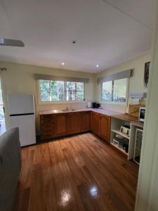 a kitchen with wooden floors and a white refrigerator at Chilverton Cottages in Ravenshoe