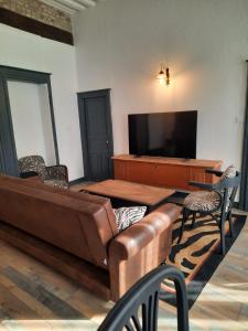 a living room with a leather couch and a flat screen tv at La belle époque in Verdun-sur-le-Doubs