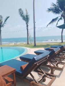 a row of lounge chairs next to a swimming pool at Baan Tasha in Laem Sor