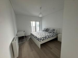 a white bedroom with a bed and a window at Vagueira Apartment in Praia da Vagueira