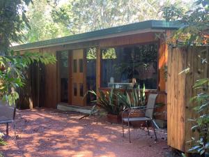 a wooden cabin with chairs in a yard at Chilverton Cottages in Ravenshoe