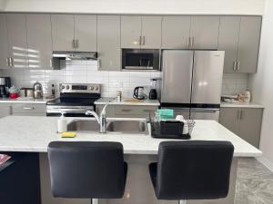 eine Küche mit weißen Schränken und einer Theke mit Stühlen in der Unterkunft Whole House 4 Bedrooms 6 beds 3 bath family friendly Quite and relaxation area in Gravenhurst