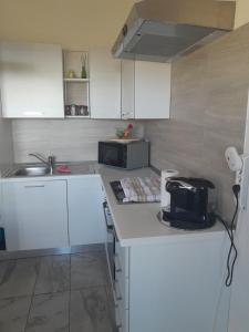 Una cocina con gabinetes blancos, un fregadero y un microondas. en belvedere, en Castelsardo