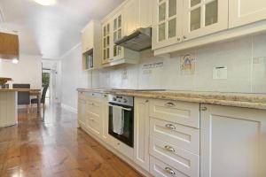 a large kitchen with white cabinets and a wooden floor at Gordonia 10 in Cape Town