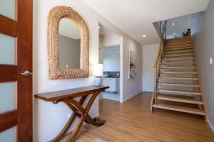 a hallway with a staircase with a mirror and a table at Chic Coastal Home on Orealla in Sunrise Beach
