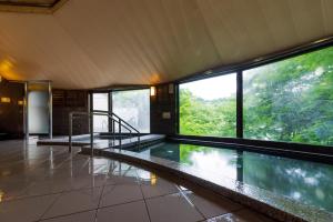 a swimming pool in a house with windows at Miyama Nature and Culture Village Kajikaso in Nakamura