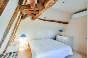 a bedroom with a white bed and wooden ceilings at Au coeur de la Dordogne, maison pour 6, piscine in La Pinsonnie +17 photos
