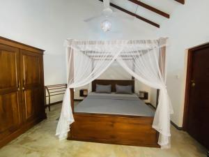 Un dormitorio con una cama con dosel y cortinas blancas. en Dana Villa, en Bentota