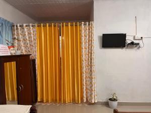 a room with a yellow curtain and a tv at Lake Homes in Varkala