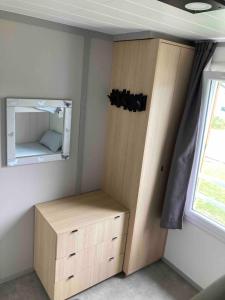 ein kleines Schlafzimmer mit einem Schrank und einem Spiegel in der Unterkunft Mobil Home piscine chauffée Pont l 'Abbe in Pont-lʼAbbé