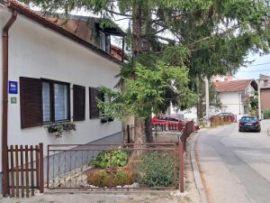 a fence in front of a house with a tree at Apartman Mario in Bihać