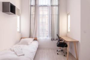 Un dormitorio con una cama y un escritorio y una ventana. en Résidence de l'Alliance, en Niza