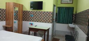 a room with a bed and a sink and a tv on the wall at Hotel Bhagwat Palace in Gaya