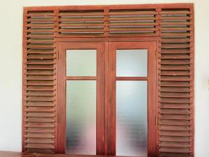 a wooden door with three windows on a wall at Sun Rise Talalla in Talalla