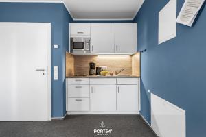 a kitchen with white cabinets and a blue wall at Ferienwohnung Bude 2 Dagebüll in Dagebüll +20 photos