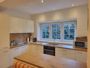 a kitchen with white cabinets and a sink and a microwave at Schmiedhäusl in Kitzbühel