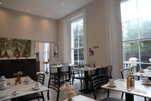 a dining room with tables and chairs and windows at Reem Hotel in London