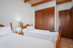 a bedroom with two beds and a wooden door at Es Ravellar - Campos in Islas Baleares +34 photos