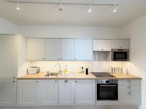 a white kitchen with white cabinets and a sink at Alma Vale Apartments 4 - Hopewell in Bristol +2 photos