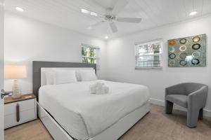 a white bedroom with a bed and a chair at Bayview Inn #101 in Bradenton Beach