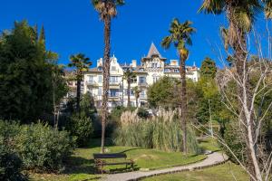 un grande edificio bianco con palme e parco di Esperia a Opatija