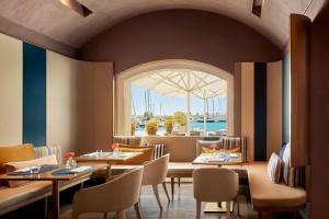 a restaurant with tables and chairs and a window at Tivoli Portopiccolo Sistiana Wellness Resort & Spa in Sistiana