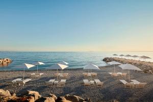 a group of chairs and umbrellas on a beach at Tivoli Portopiccolo Sistiana Wellness Resort & Spa in Sistiana