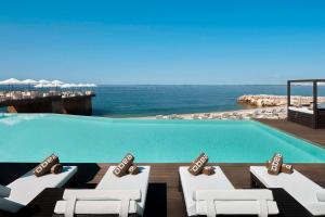 a swimming pool with lounge chairs and the ocean at Tivoli Portopiccolo Sistiana Wellness Resort & Spa in Sistiana