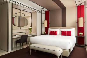 a bedroom with a white bed with red pillows and a desk at Tivoli Portopiccolo Sistiana Wellness Resort & Spa in Sistiana