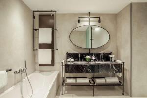 a bathroom with a tub and a sink and a mirror at Tivoli Portopiccolo Sistiana Wellness Resort & Spa in Sistiana
