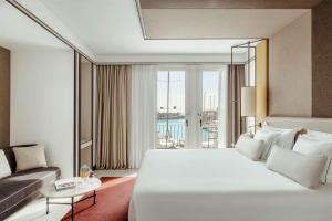 a bedroom with a large white bed and a couch at Tivoli Portopiccolo Sistiana Wellness Resort & Spa in Sistiana