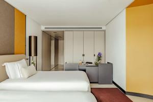 a bedroom with a white bed and a desk at Tivoli Portopiccolo Sistiana Wellness Resort & Spa in Sistiana