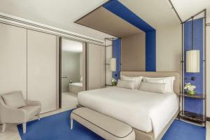 a bedroom with a large white bed and a chair at Tivoli Portopiccolo Sistiana Wellness Resort & Spa in Sistiana