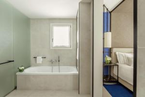 a bathroom with a bath tub and a window at Tivoli Portopiccolo Sistiana Wellness Resort & Spa in Sistiana