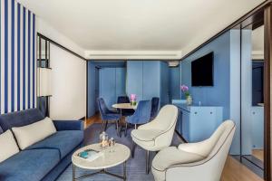 a living room with a blue couch and chairs and a table at Tivoli Portopiccolo Sistiana Wellness Resort & Spa in Sistiana