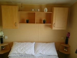 a bedroom with wooden cabinets and a bed with white sheets at Highfields Rio 6 berth blow heated in Skegness