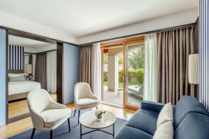 a living room with a blue couch and a bedroom at Tivoli Portopiccolo Sistiana Wellness Resort & Spa in Sistiana
