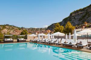 a pool at a hotel with chairs and umbrellas at Tivoli Portopiccolo Sistiana Wellness Resort & Spa in Sistiana