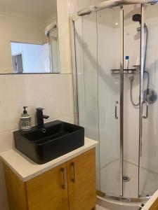 a bathroom with a black sink and a shower at Guesthouse in Half Moon Bay in Auckland
